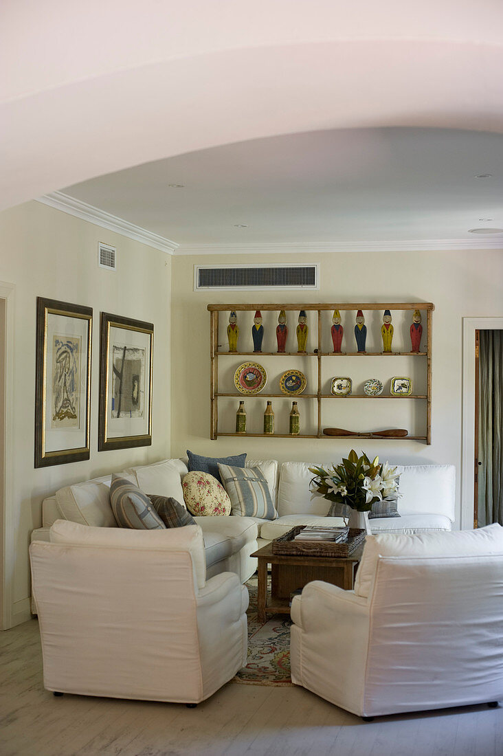 Seating area in country-house style with white corner sofa and loose-covered armchairs