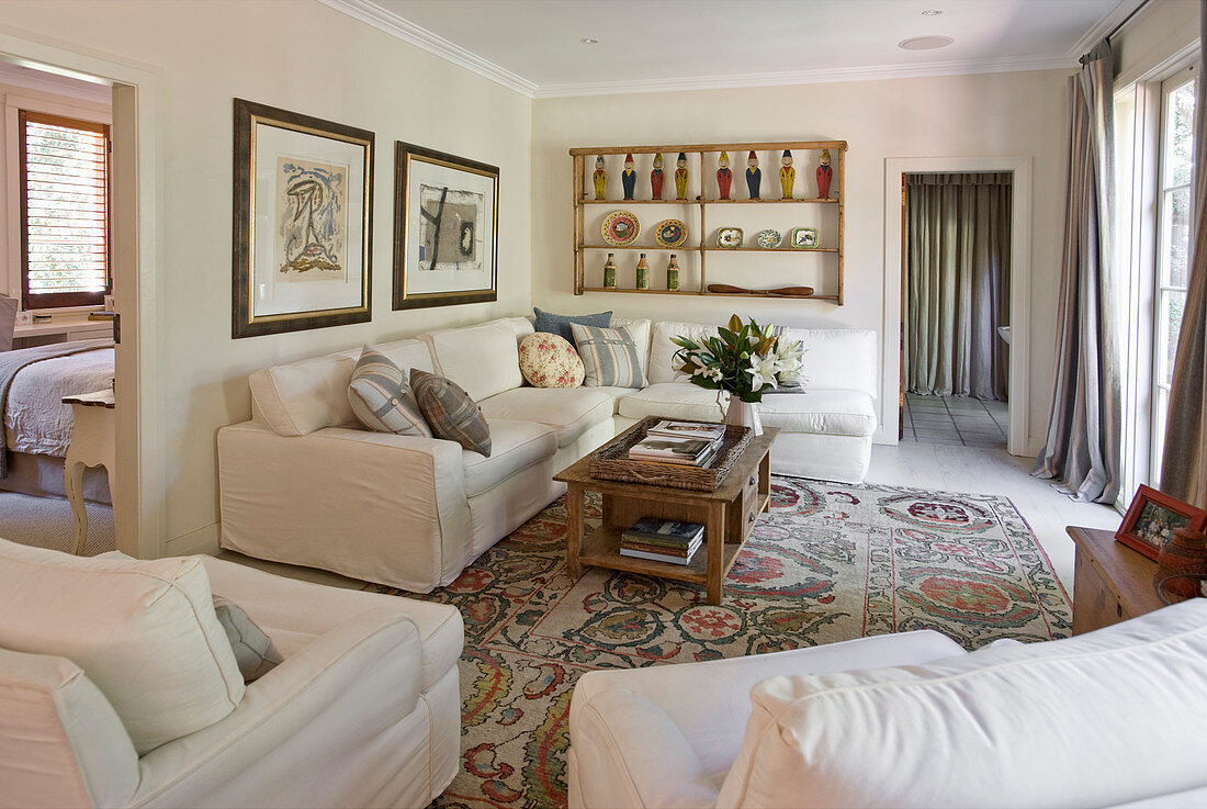 White corner sofa and armchairs around wooden coffee table in country-house-style living room