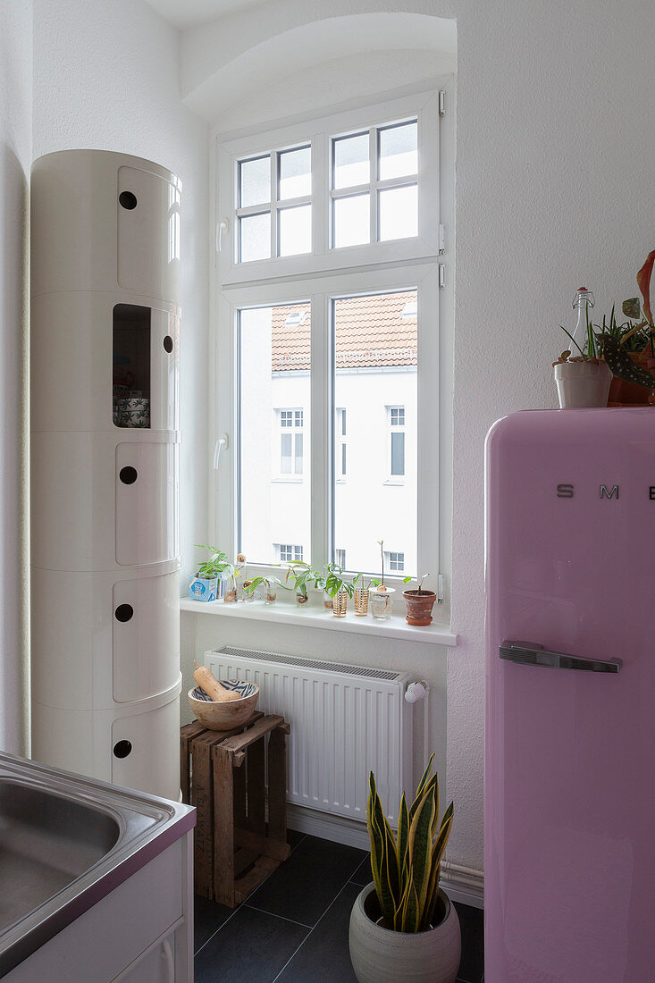 Rosa Kühlschrank neben Fenster und runder Schrank in der Küche