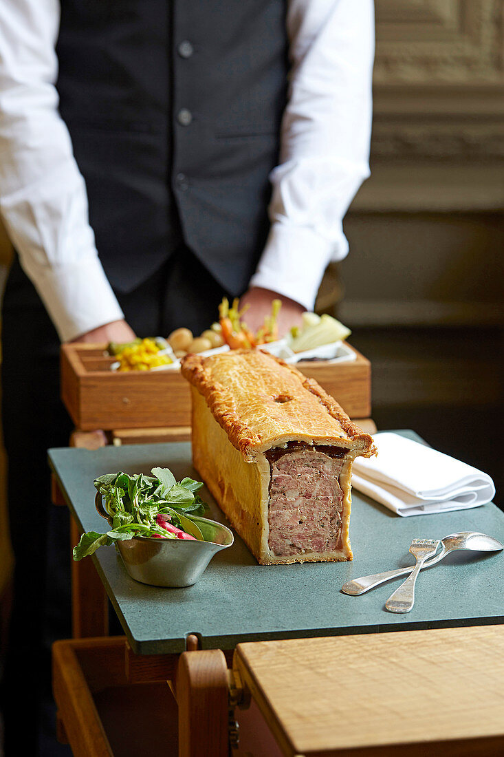 A waiter serving a meat pie