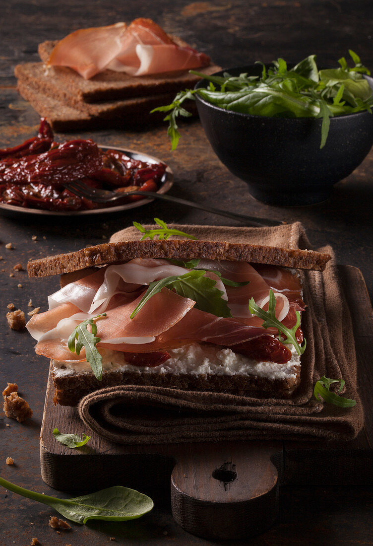 Cured ham in bread with goat's cheese, rocket and dried tomatoes