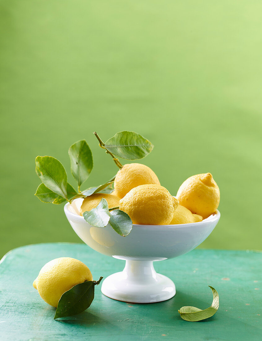 Zitronen mit Blatt in weisser Schale