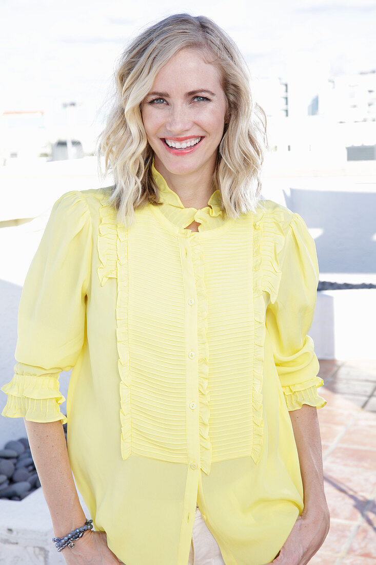 A blonde woman wearing a frilly yellow blouse