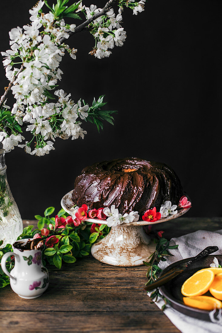 Schokoladen-Kranzkuchen dekoriert mit Obstblüten auf Kuchenständer