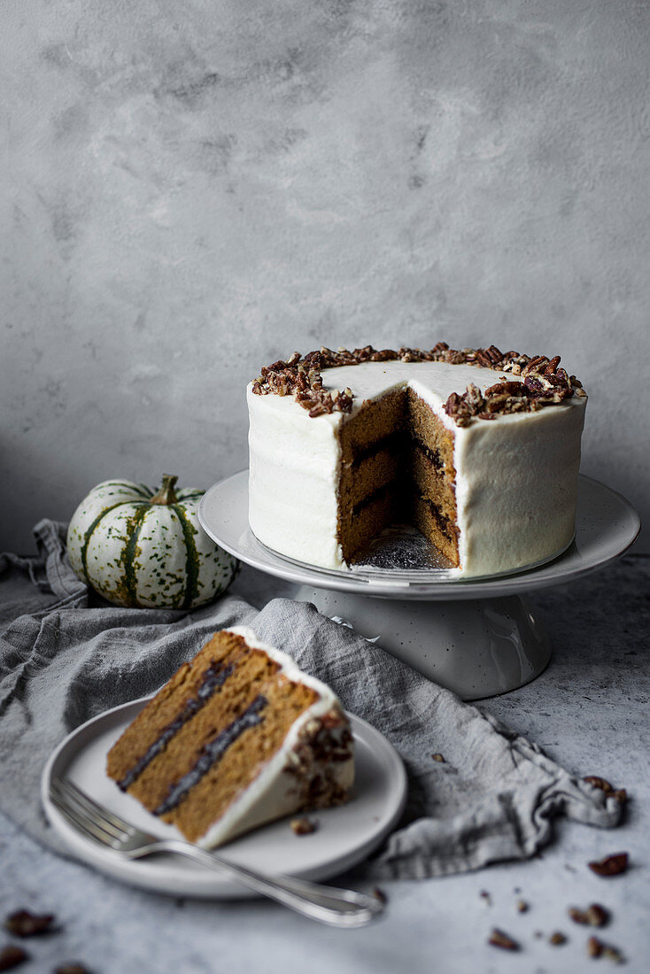 Pumpkin Spice Cake With Chocolate Ganache and Maple Cream Cheese Frosting Decorated With Crushed Pecans