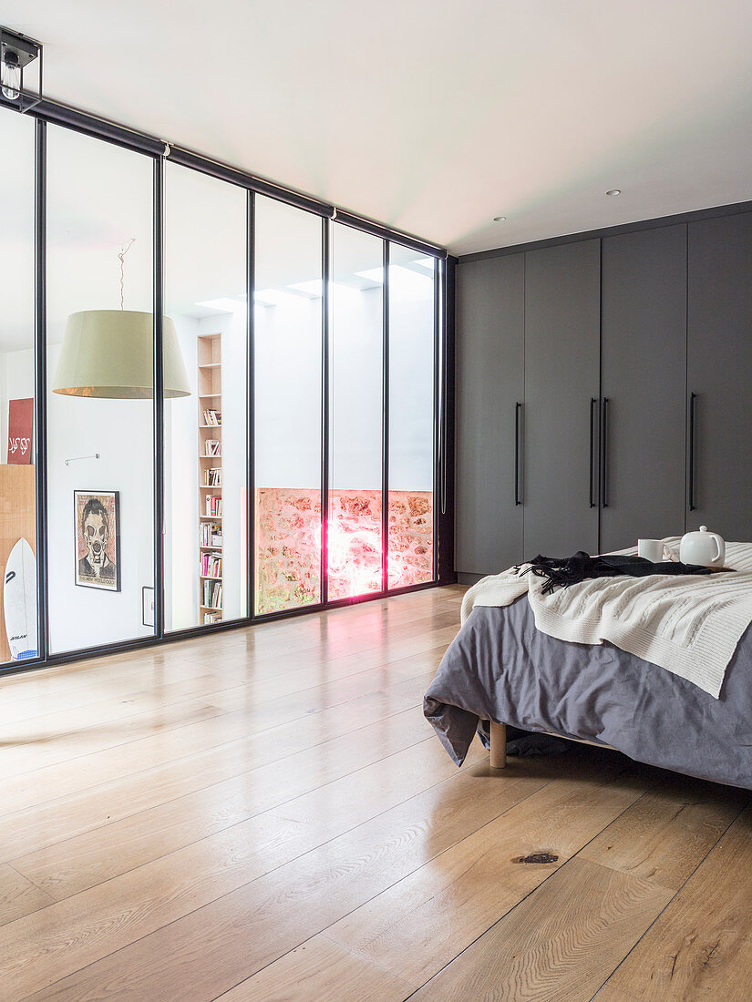 Double bed and grey fitted wardrobes in bedroom in glazed gallery