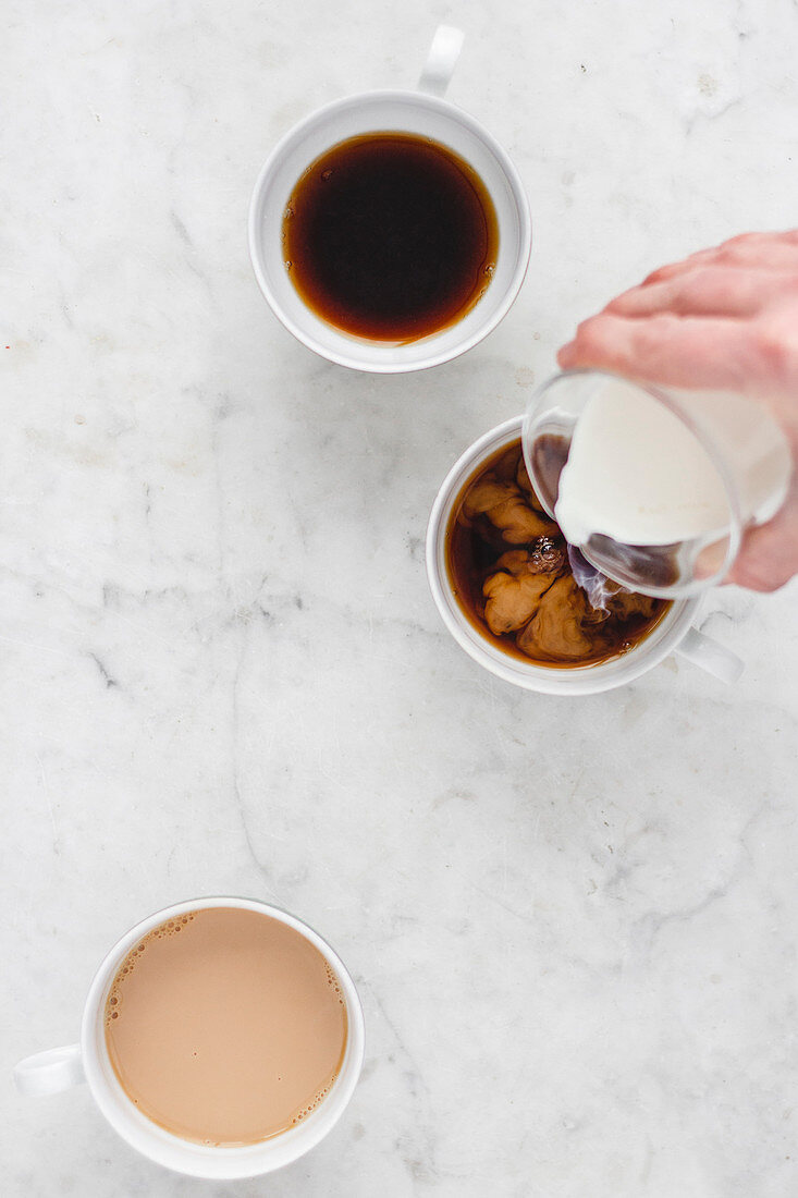 Three coffee cups with coffee and milk