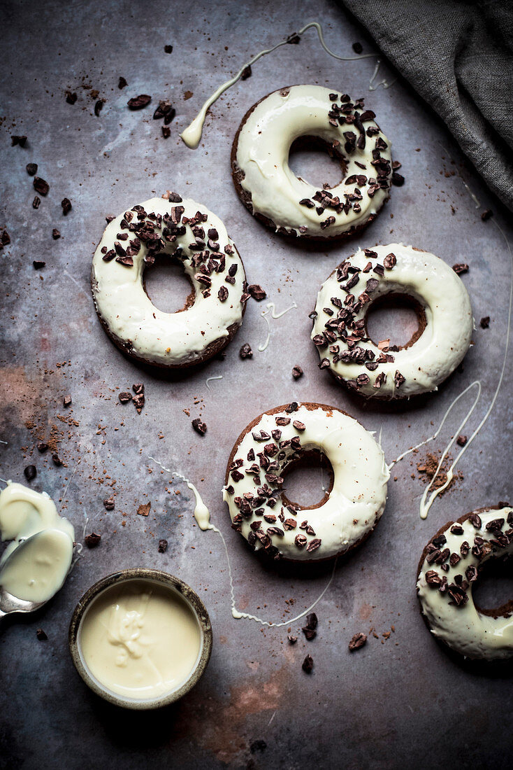 Gebackene Donuts mit weißer Schokoglasur und Kokaonibs
