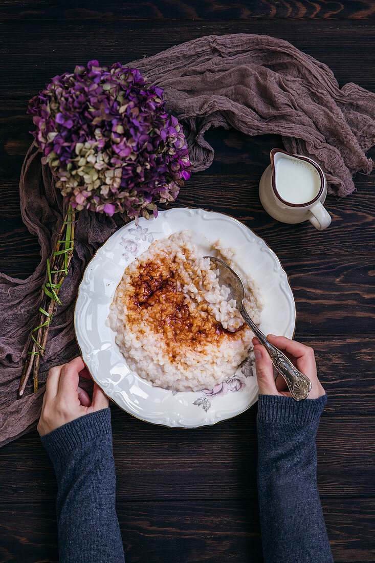 Woman eating rice pudding sprinkled with sugar and cinnamon