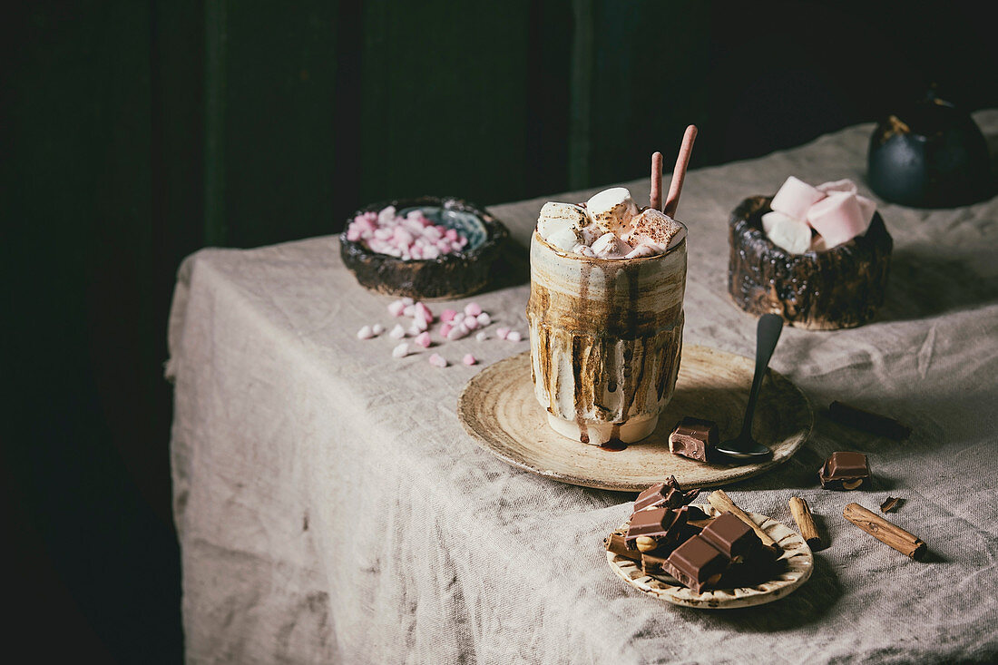 Ein Glas heiße Schokolade mit Sahne und Marshmallows auf Tisch