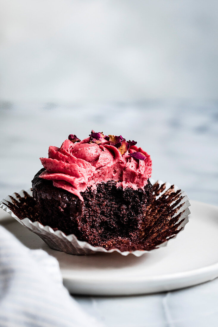 Schokoladen-Cupcake mit rosa Frosting, angebissen