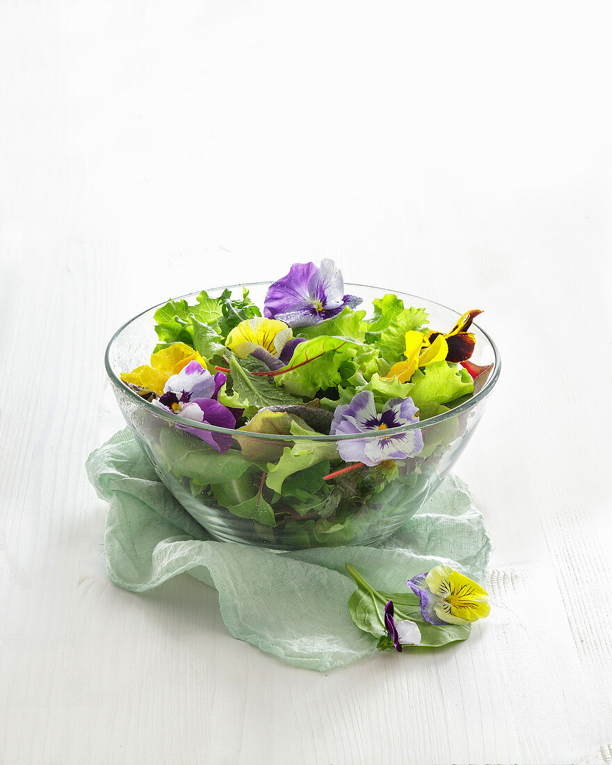 Pflücksalat und Essblüten in einer Glasschüssel