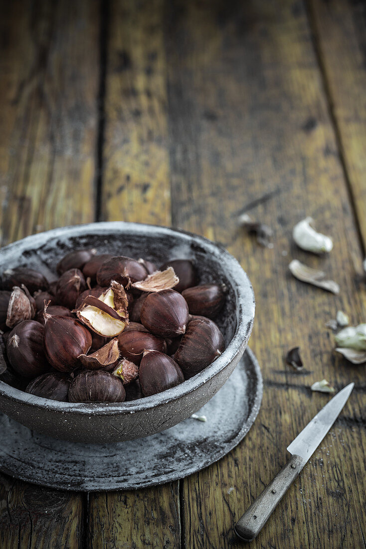Chestnuts in a clay bowl on a wooden background