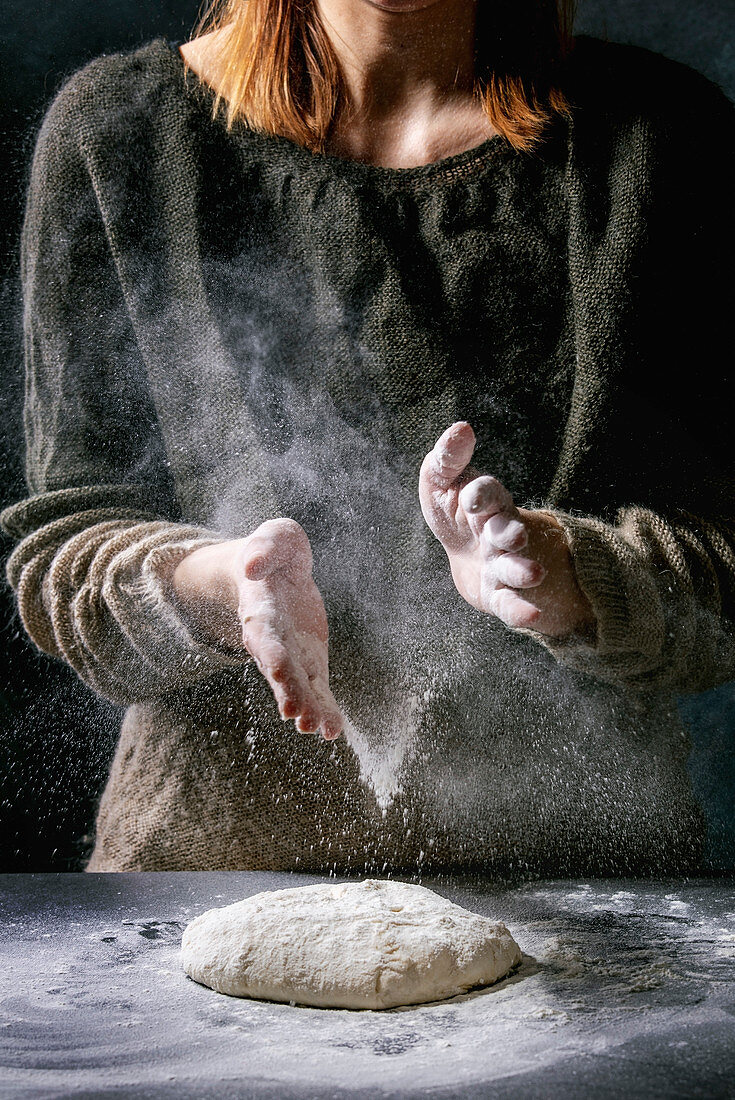 Process of making homemade bread dough: Female hands sprinkles flour