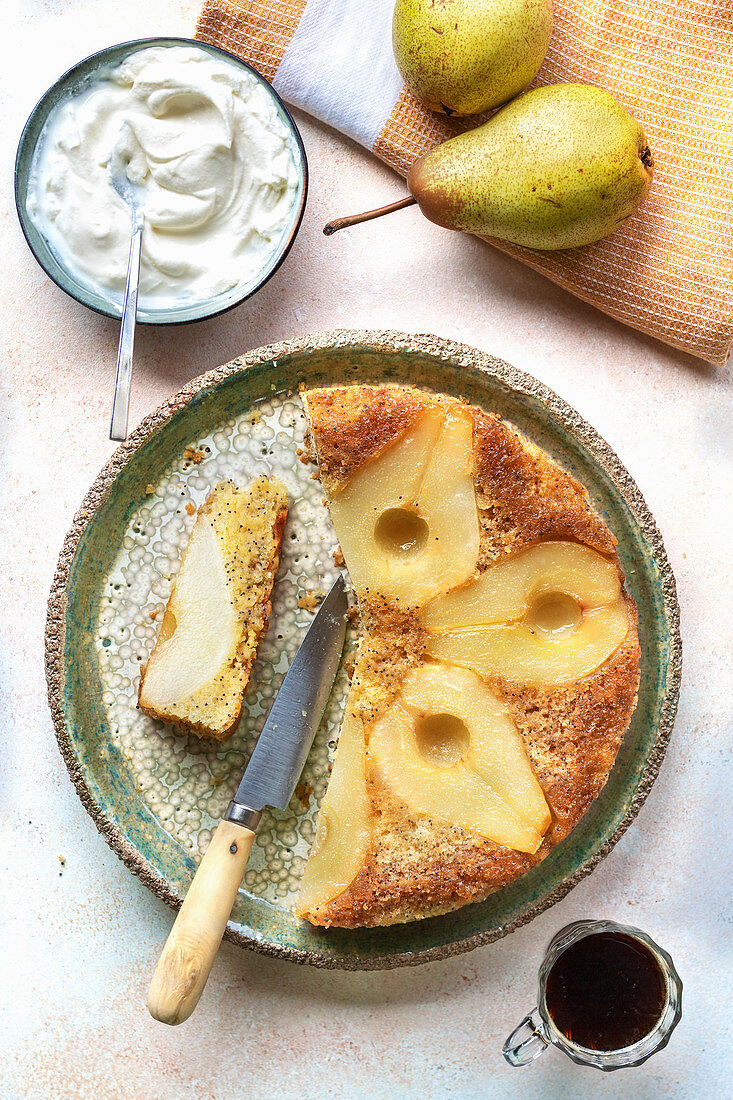 Upside down pear cake with whipped cream and a cup of coffee on the table