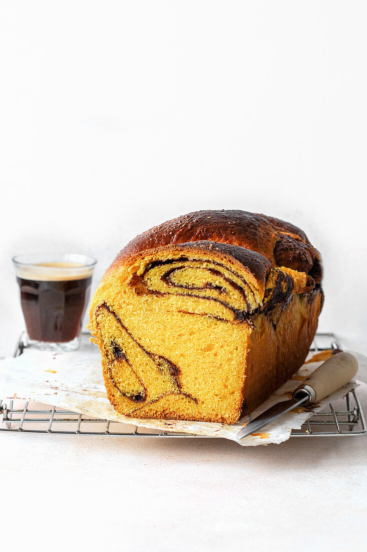 Pumpkin brioche and a cup of coffee on a wire rack
