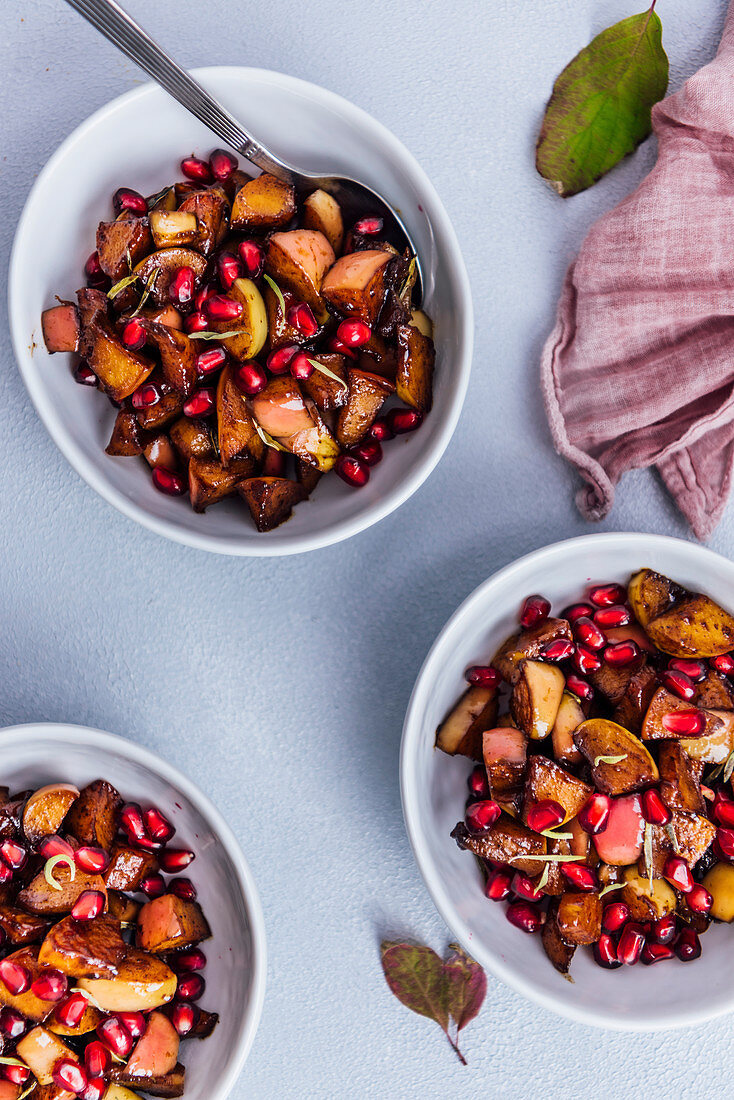 Spiced apple compote garnished with pomegranate arils served in three white bowls