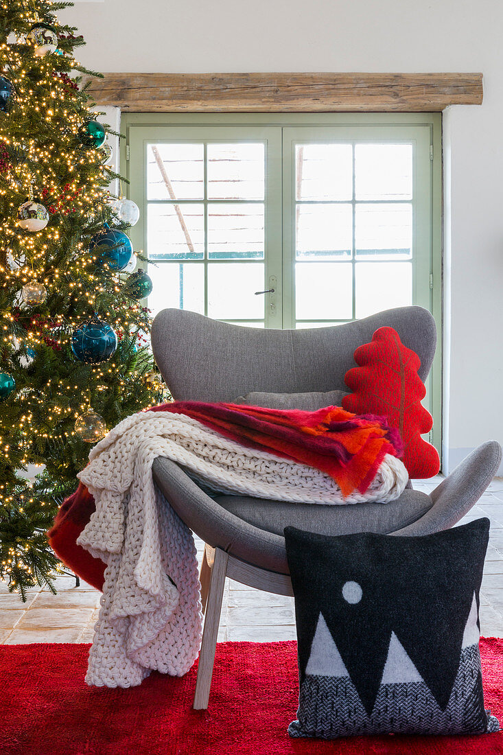 Cushions and blankets on grey modern easy chair in front of Christmas tree