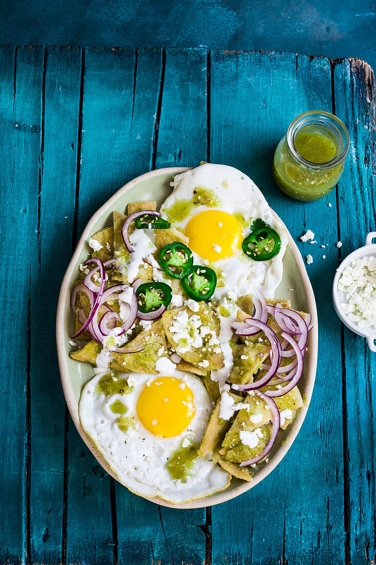 Chilaquiles and eggs with jalapeno and tomatillo sauce (Mexican fried corn chips with tomatillo sauce, sour cream, cheese, and onions)