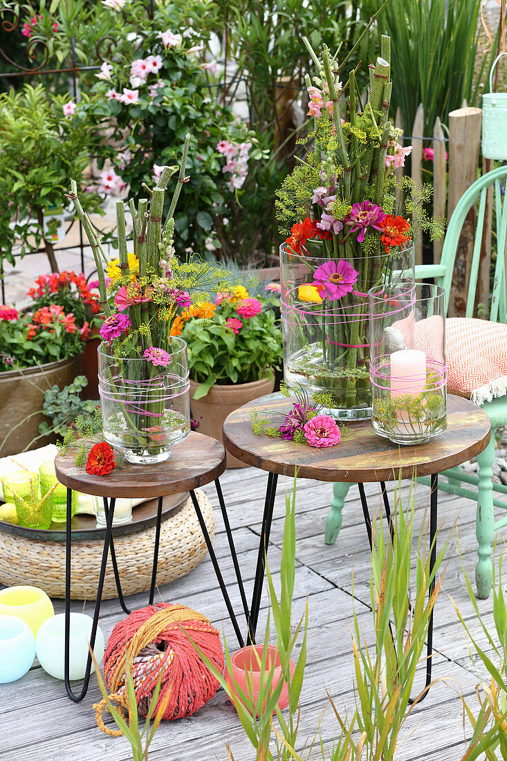 Vasen mit Gestecken aus Knöterich und Blumen auf dem Tisch auf der Terrasse