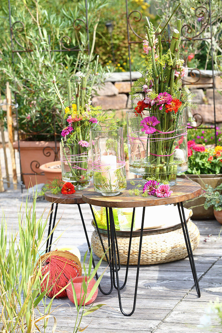 Arrangements of knotweed and flowers in vases on table on terrace