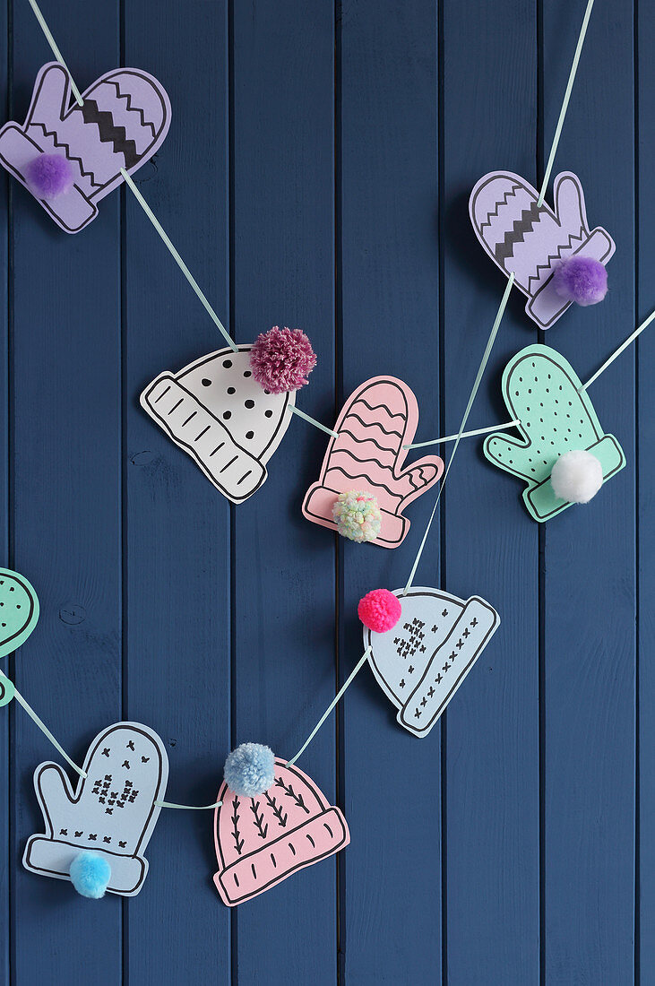 Garland of paper gloves and hats with pompoms