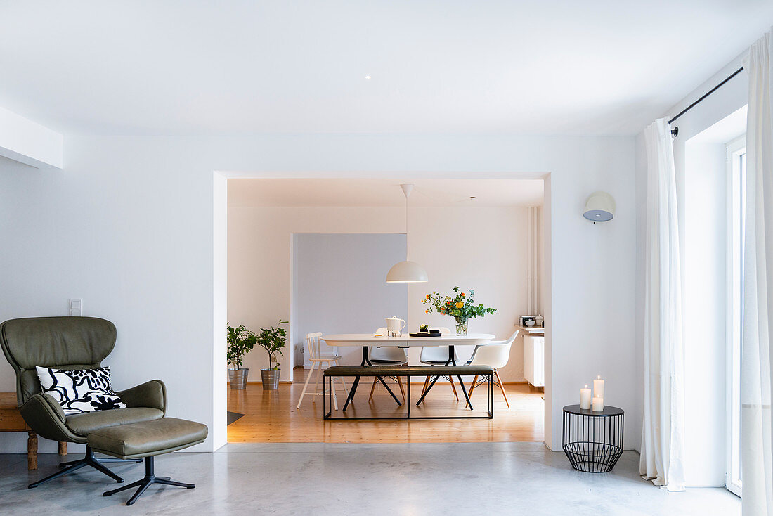 Ledersessel mit Fußschemel in hellem Wohnzimmer, Blick ins Esszimmer