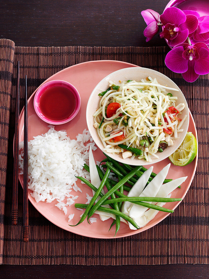 Salat aus grüner Papaya serviert mit Fischsauce, grünen Bohnen und Reis