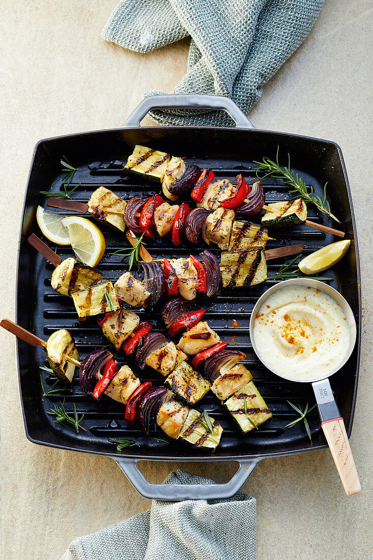 Chicken skewers with peppers and red onions in a grill pan