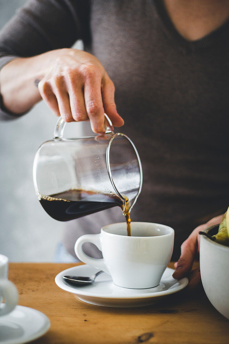 Woman's hand pouring coffee into a coffee cup