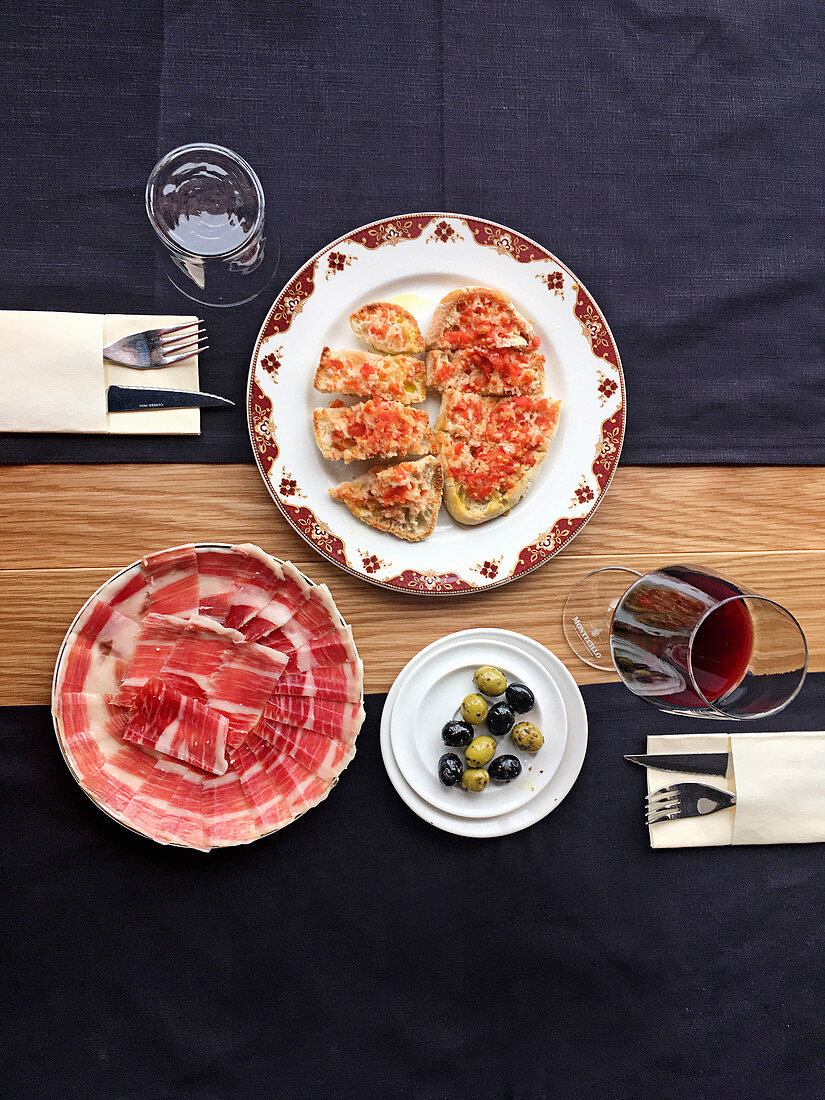 Tomatenbrote, Iberico-Schinken, Oliven und ein Glas Rotwein