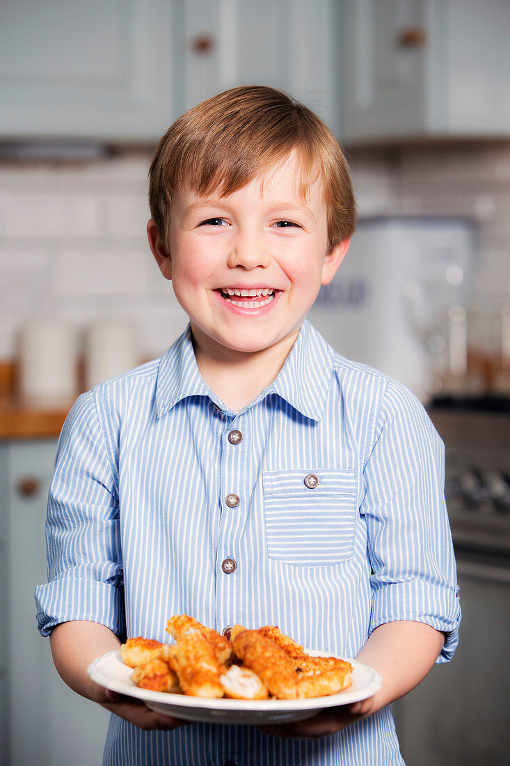 Boy holding plate with chicken schnitzel strips