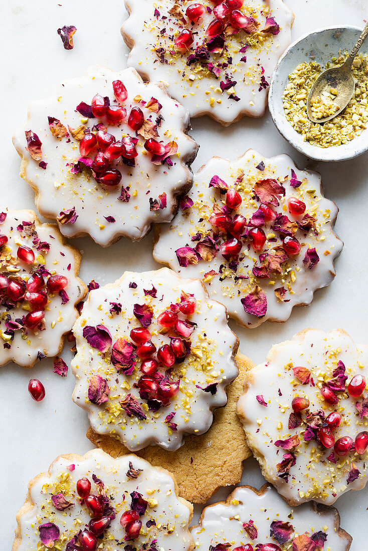 Cookies with icing, pomegranate seeds and rose petals