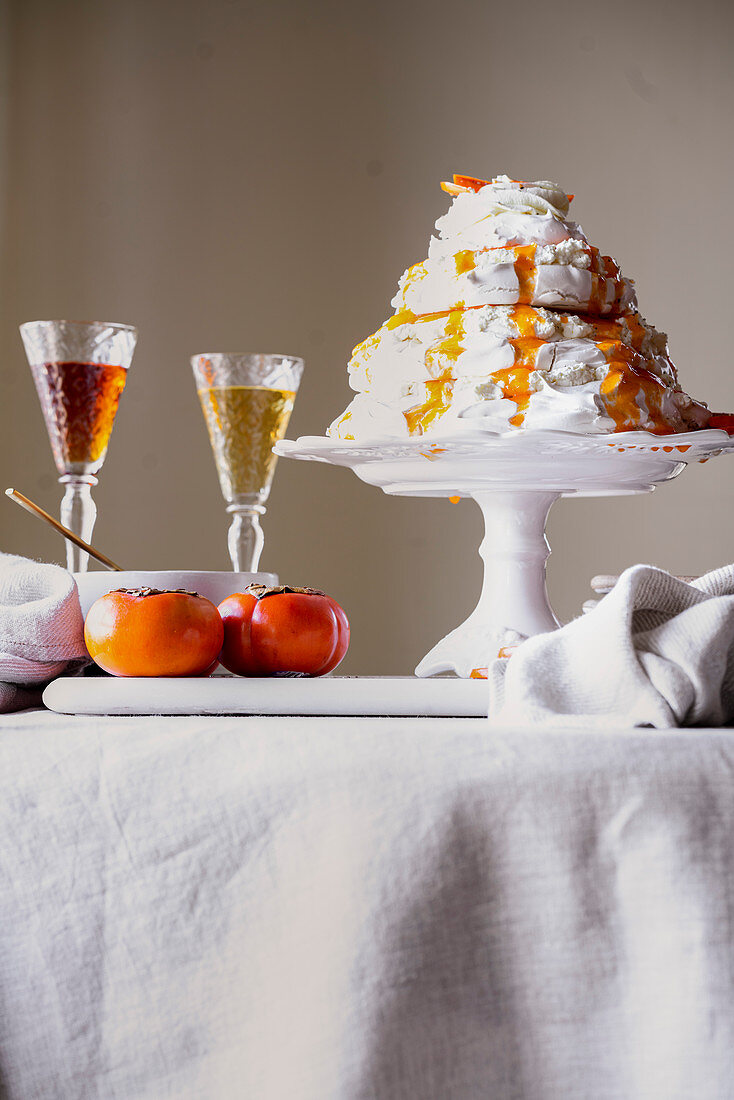 Pavlova cake with cardamom and sharon fruit puree on a cake stand