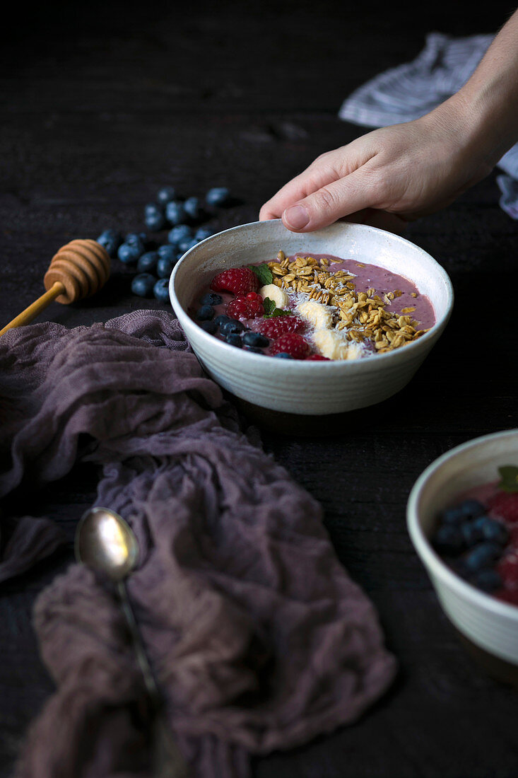 Hand holding an acai smoothie bowl