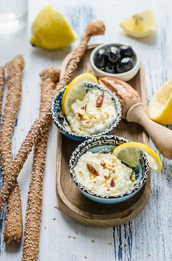 Fetadip mit Zitrone und Chilipfeffer serviert dazu Brotsticks und Oliven