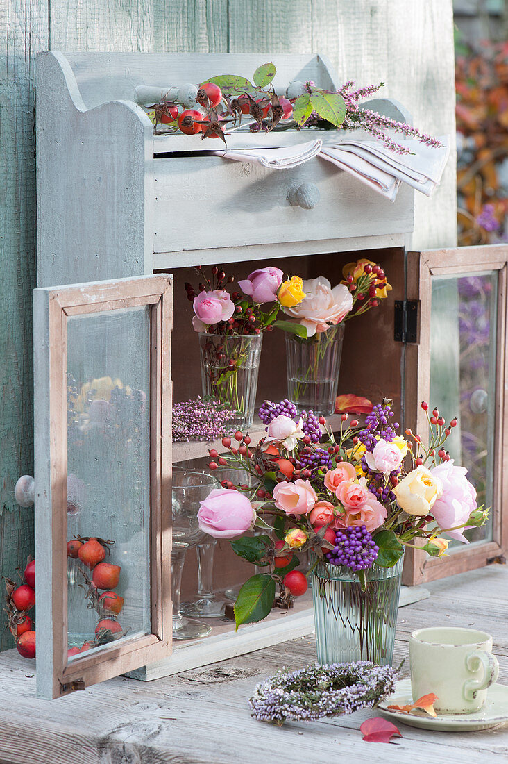 Autumn bouquets of roses with rose hips and berries from the love pearl bush, wreaths from bud heather and rose hips
