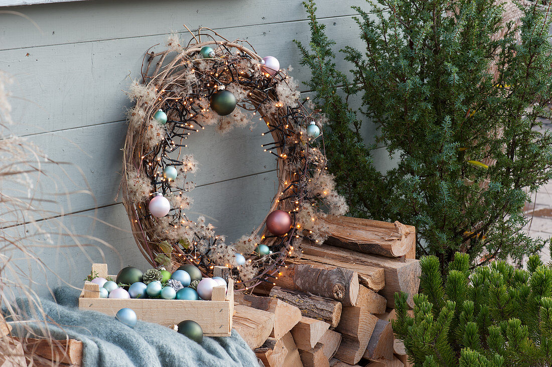 Clematis wreath, decorated with fairy lights and balls on firewood