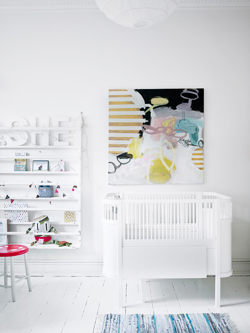 Abstract painting above cot in white nursery