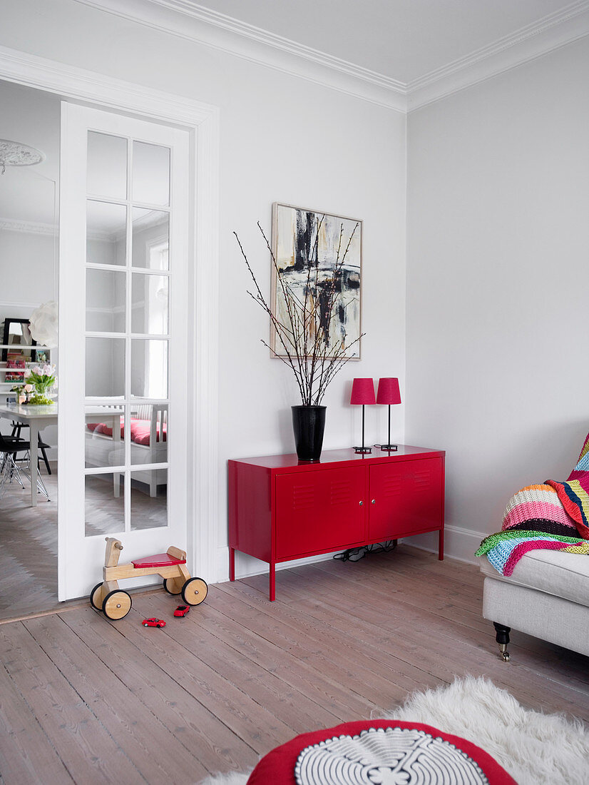 Rotes Sideboard aus Metall und Rutschwagen im Wohnzimmer