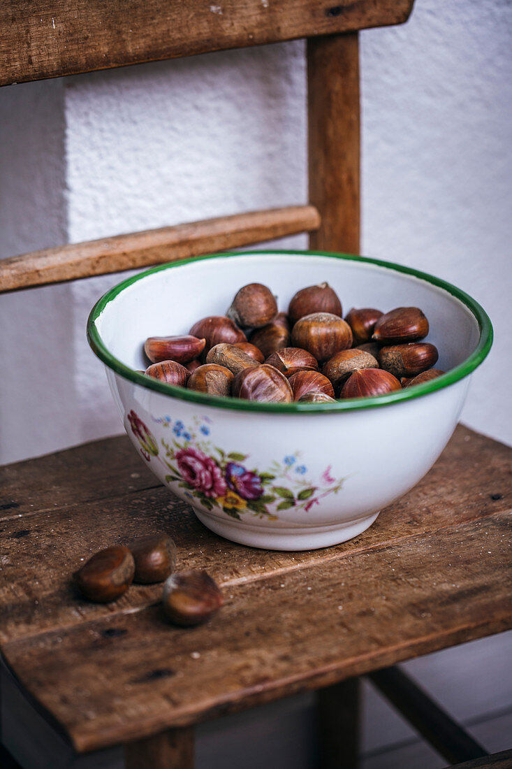 Fresh chestnuts in a vintage bowl on a wooden chair