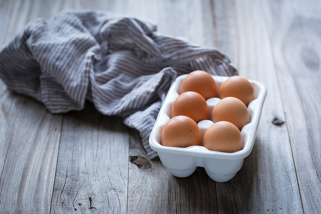 Sechs braune Eier in Porzellan-Eierträger
