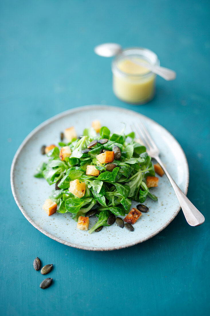 Feldsalat mit Kartoffel-Knoblauch-Dressing, gerösteten Kürbiskernen und Croûtons