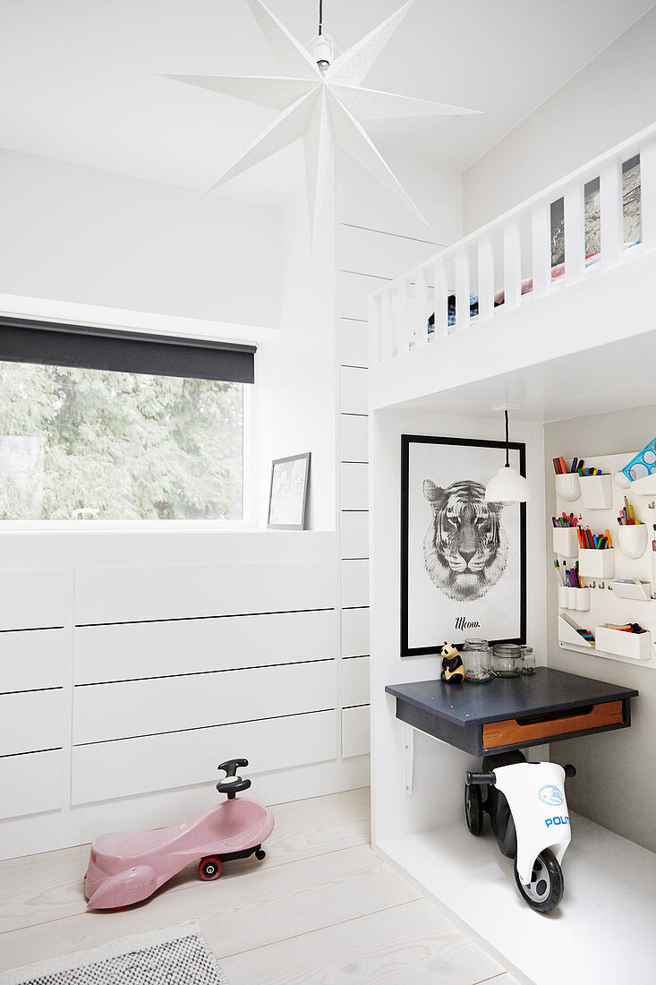 Ride-on toys and desks below white loft bed in child's bedroom