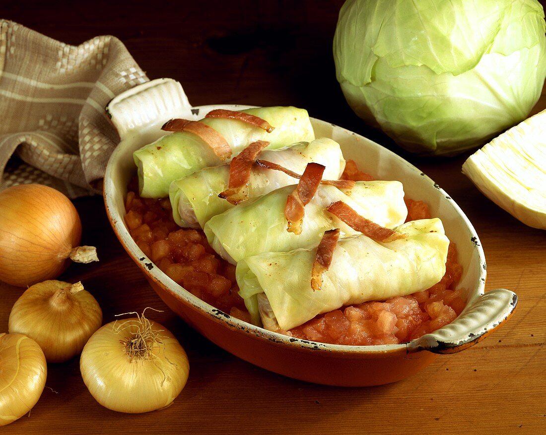 Cabbage roulades with bacon strips on tomatoes