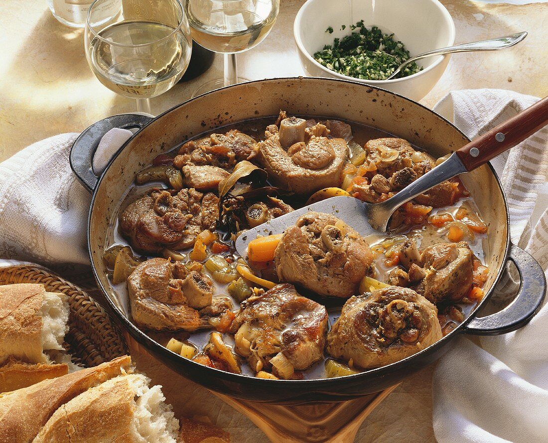 Braised turkey leg pieces with vegetables in a pan