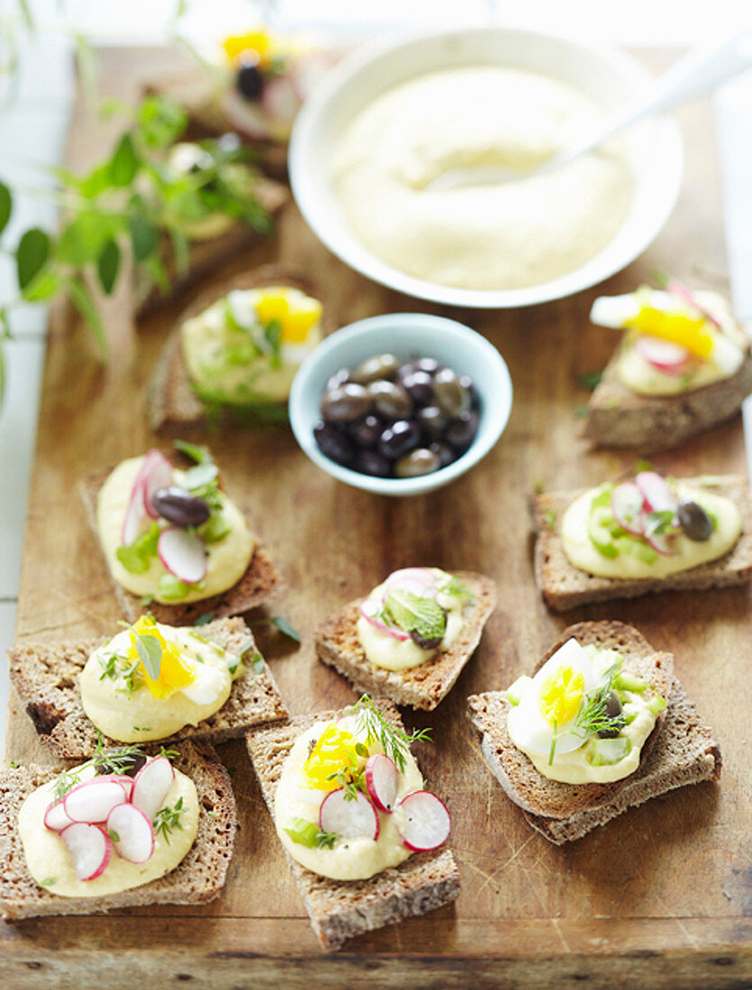 Canapés with chickpea cream, radishes and olives