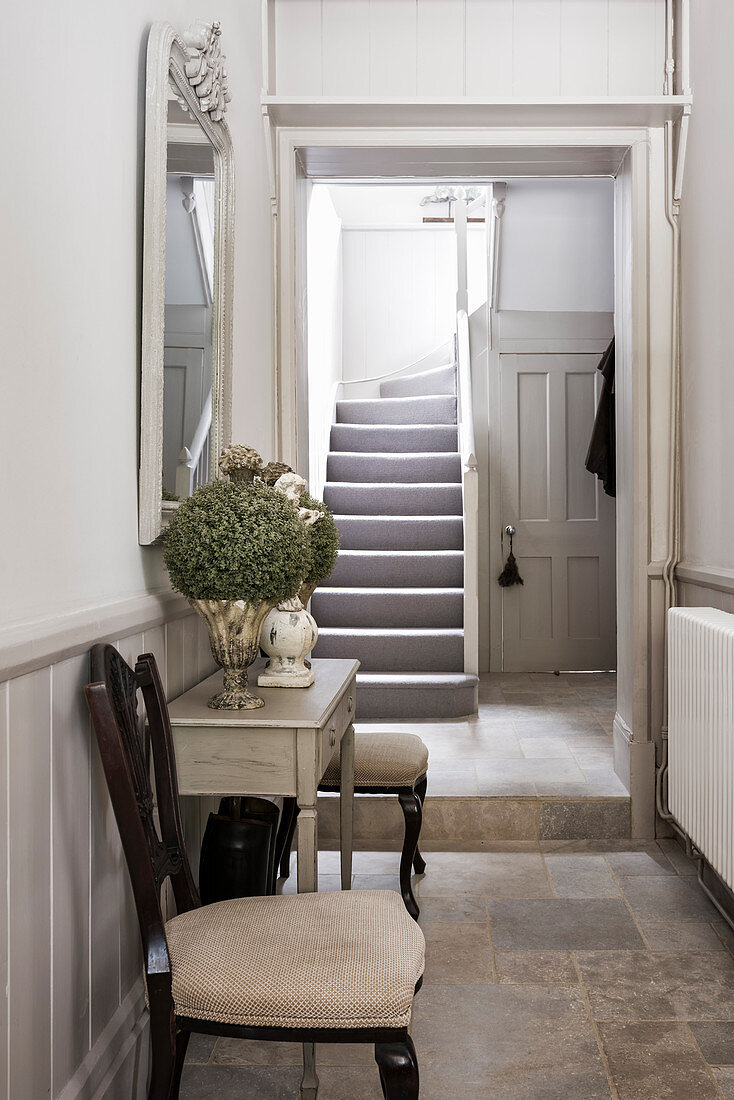 Upholstered chairs and console with mirror in tiled hallway