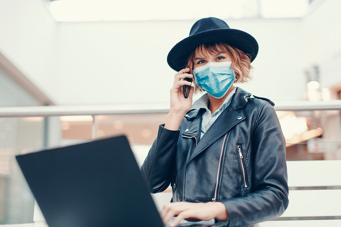 Busy woman in face mask making phone call