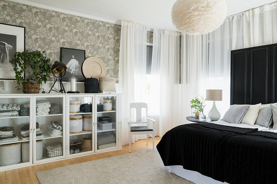 Double bed with screen as bed headboard and linen cupboard made from old windows in the bedroom